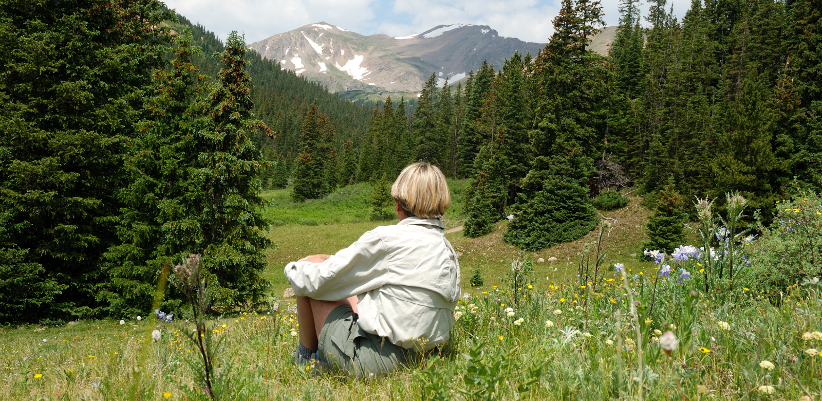 Boy in field of flowers overlooking mountains