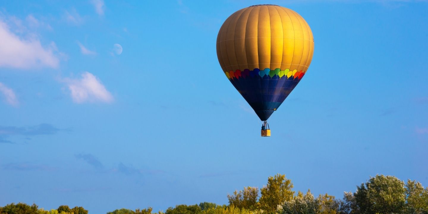 A yellow hot air balloon floating over Pagosa Springs, Colorado
