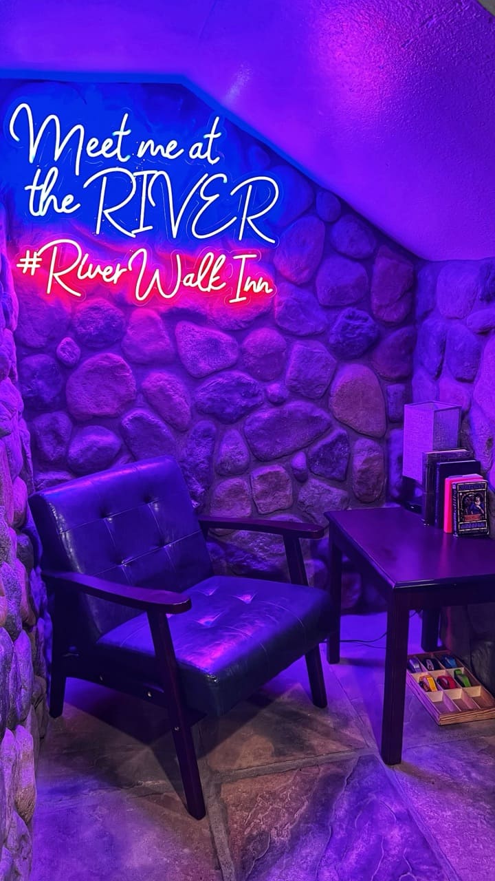 A neon sign that says Meet me at then River #RiverWalkInn at our Pagosa Springs Hotel