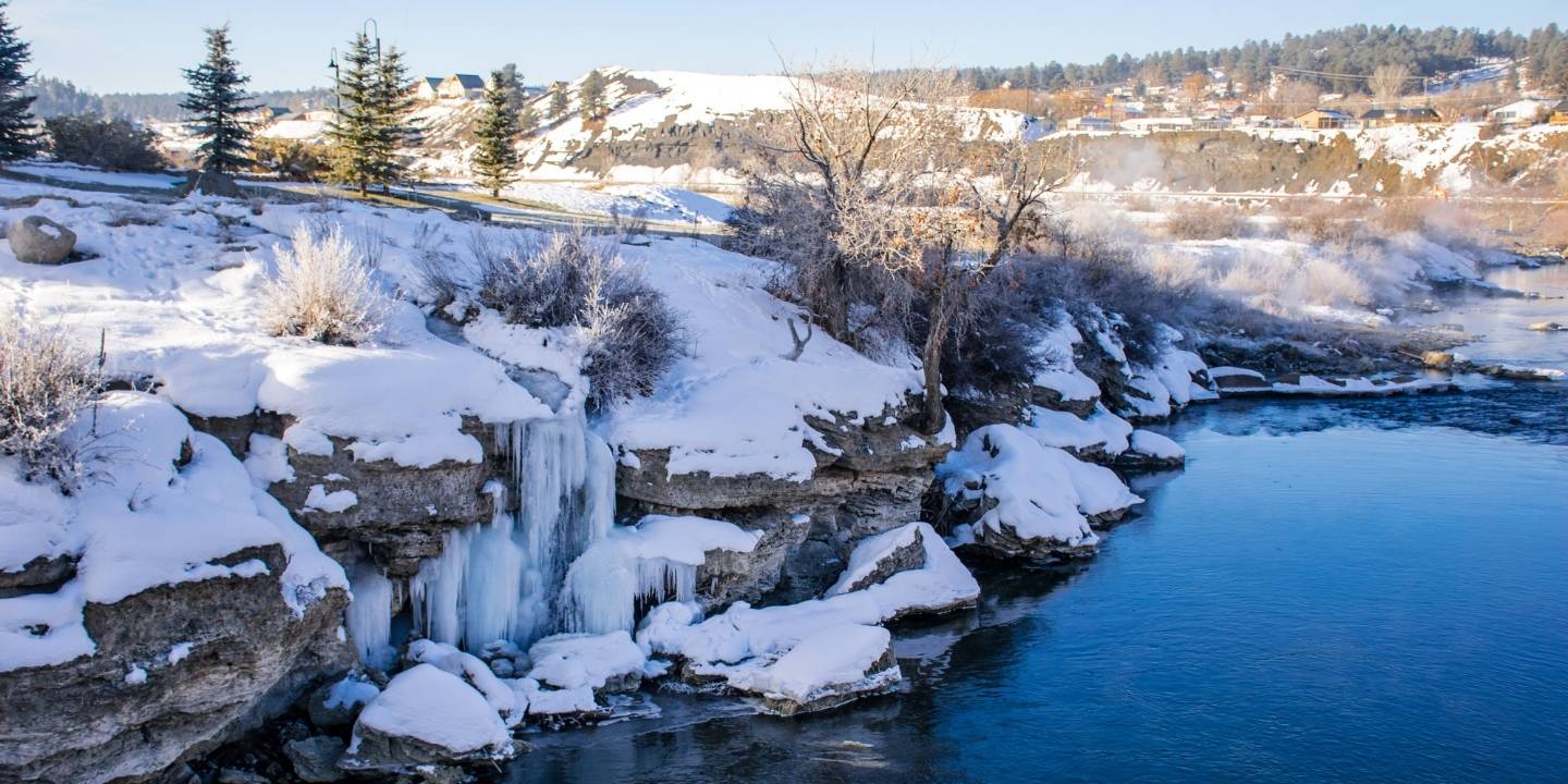 A frozen waterfall and snow-covered riverbank during winter in Pagosa Springs, Colorado