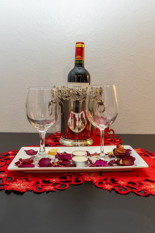 Two wine glasses sitting on a dish with rose petals in front of a bottle of wine chilling in an ice bucket for Valentine's Day Weekend Getaways in Colorado