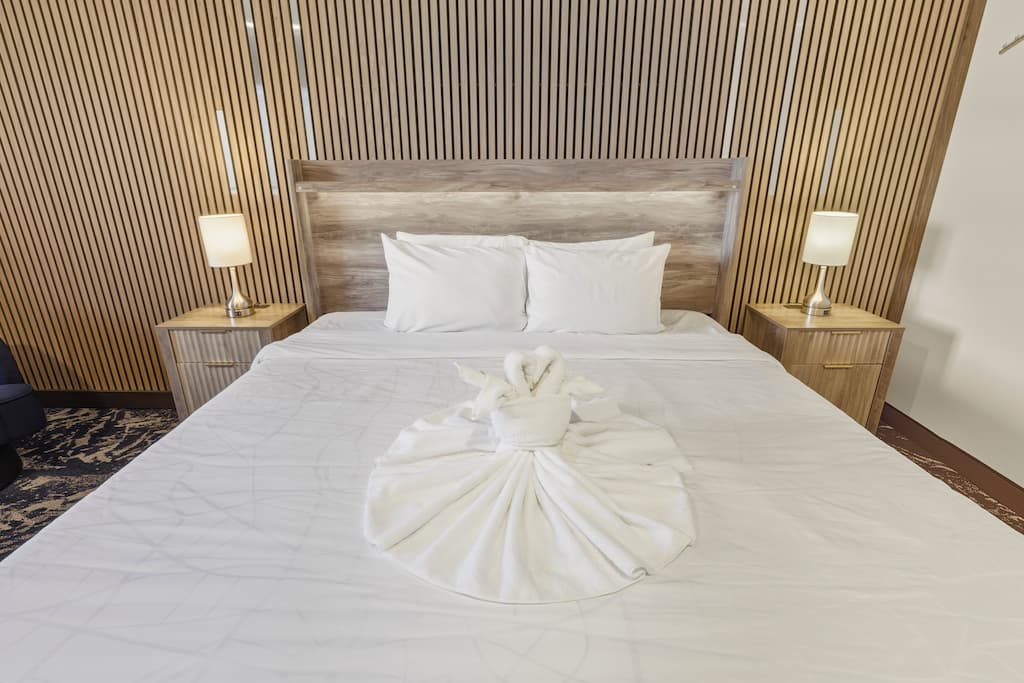 A king bed with a wooden accent wall behind it at our Pagosa Springs Hotel