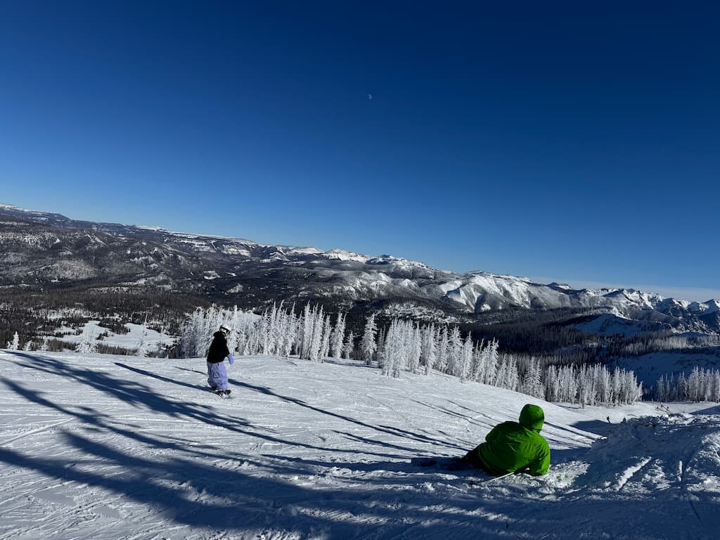 Two snowboarders resting on a snow-covered hill at Wolf Creek Ski Area